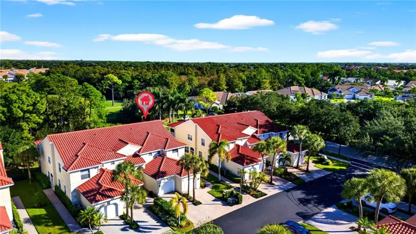 Multi-unit residential structure featuring a red tile roof, light-toned stucco exterior, and attached garages
