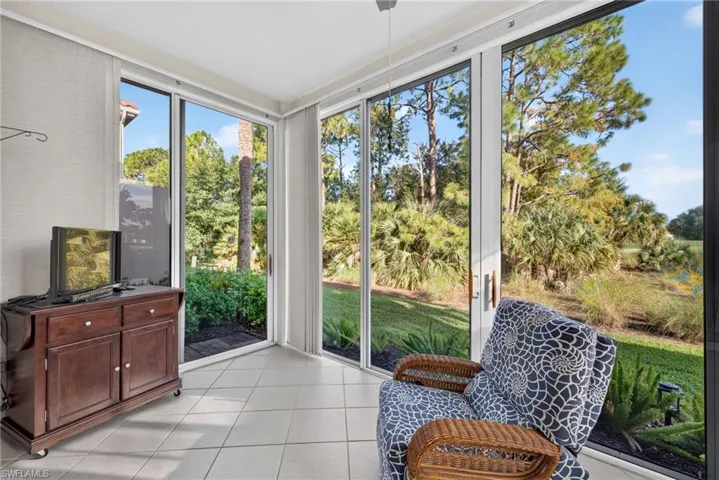 Enclosed sunroom featuring light-toned tile flooring, floor-to-ceiling glass paneling, and multiple sliding glass doors