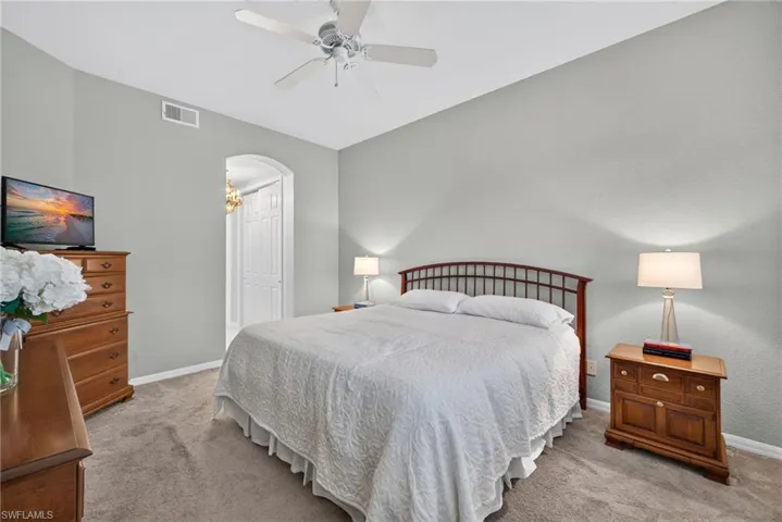 Neutral-toned walls, arched entryway, and a central ceiling fan with integrated lighting