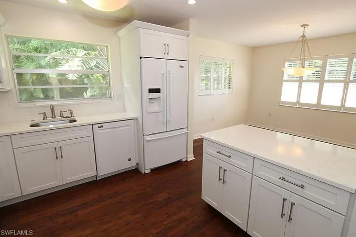 Kitchen featuring white cabinetry, white appliances, hanging light fixtures, tasteful backsplash, and light stone counters