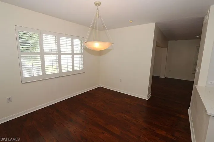 Unfurnished room featuring dark wood-type flooring and baseboards