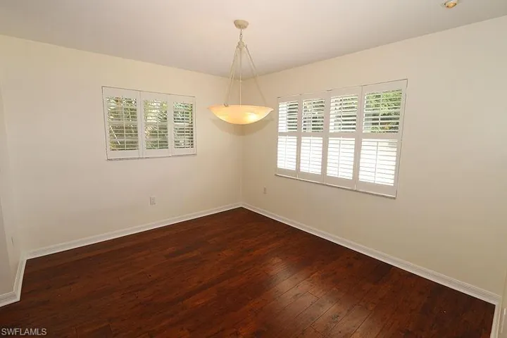 Spare room featuring baseboards and dark wood-style floors