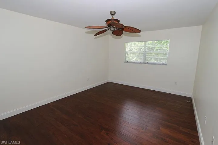 Unfurnished room featuring dark wood finished floors and a ceiling fan