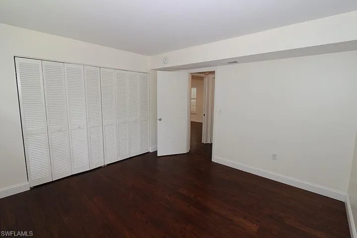 Unfurnished bedroom with dark wood-style flooring and a closet
