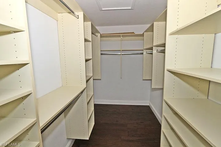 Walk in closet with dark wood-style floors and attic access