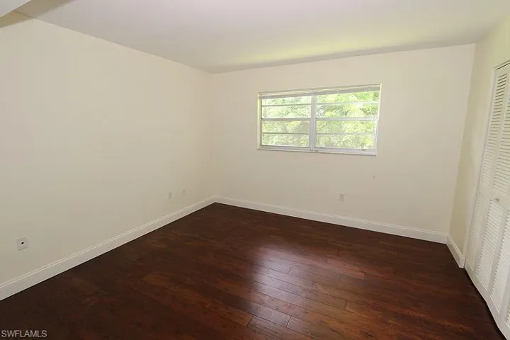 Unfurnished bedroom featuring dark wood-style flooring and a closet