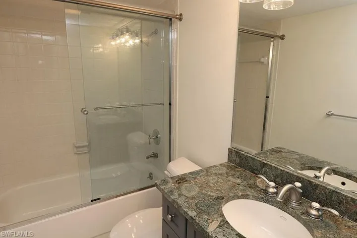 Bathroom with shower / bath combination with glass door and vanity