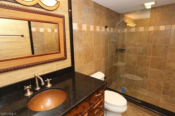 Bathroom featuring tile walls, tiled shower, and vanity