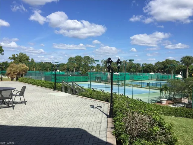 View of tennis court with a patio area