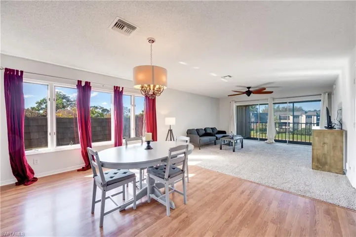 Dining room featuring light wood-style flooring, hanging lights, ceiling fan, and a textured ceiling