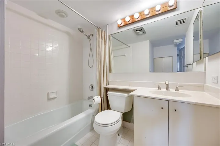 Full bath with vanity, light tile patterned floors, and shower / tub combo
