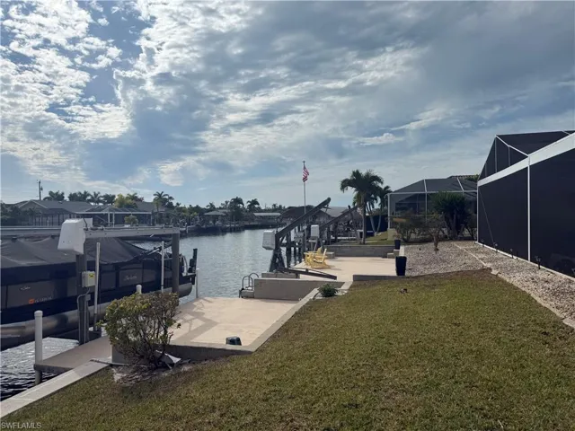 Dock featuring a lawn, a water view, boat lift, and a lanai