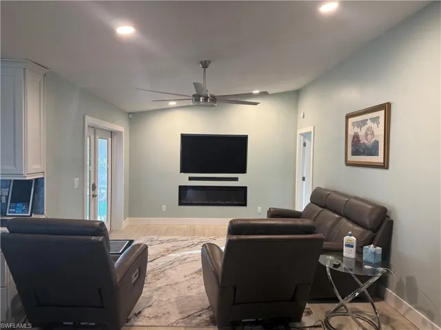 Living area featuring ceiling fan, a glass covered fireplace, light wood finished floors, and recessed lighting