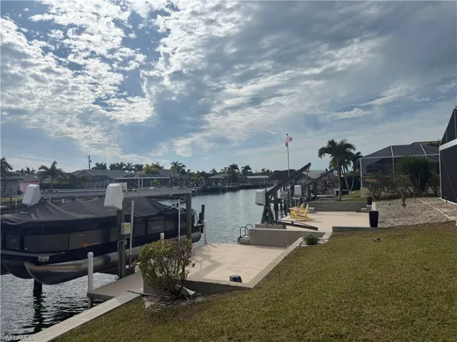 Dock with a lawn, boat lift, and a water view