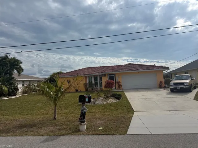 View of front of property with driveway, a front lawn, a tile roof, and a garage