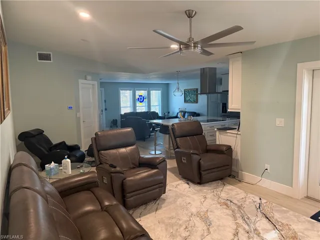 Living area with ceiling fan and light wood-type flooring