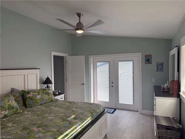 Bedroom featuring french doors, access to outside, light wood-style flooring, a ceiling fan, and lofted ceiling