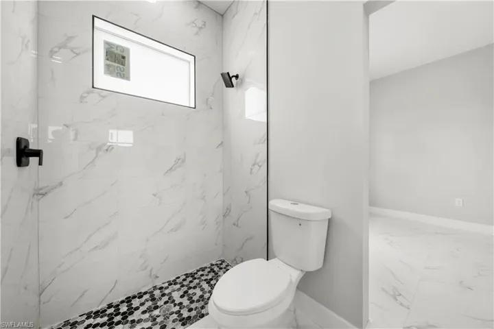 Bathroom with marble look tile flooring and a tile shower