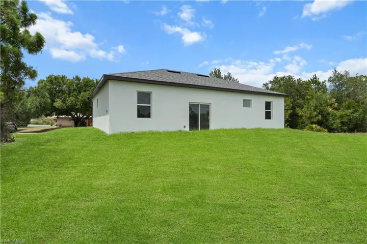 Back of house with stucco siding and a lawn