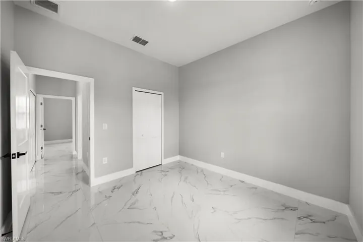 Unfurnished bedroom with light marble finish floors and a closet