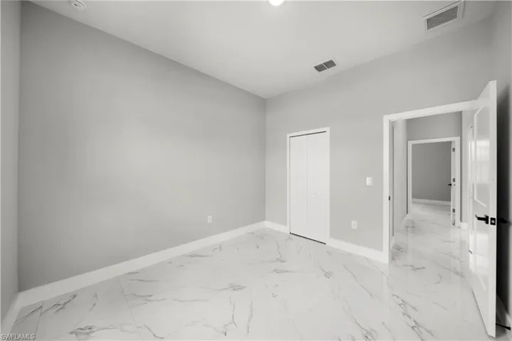 Unfurnished bedroom with light marble finish flooring and a closet