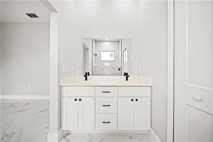 Bathroom with marble finish flooring, double vanity, and a marble finish shower
