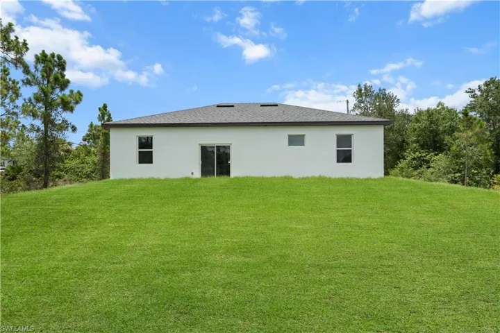 Back of property with a lawn and stucco siding