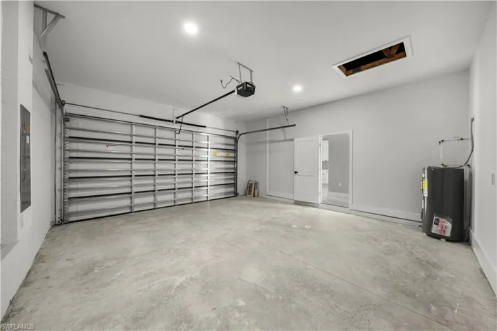Garage with water heater, a garage door opener, and recessed lighting