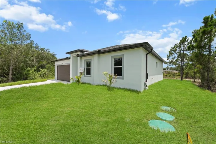 View of front of home with an attached garage, driveway, a front lawn, and stucco siding