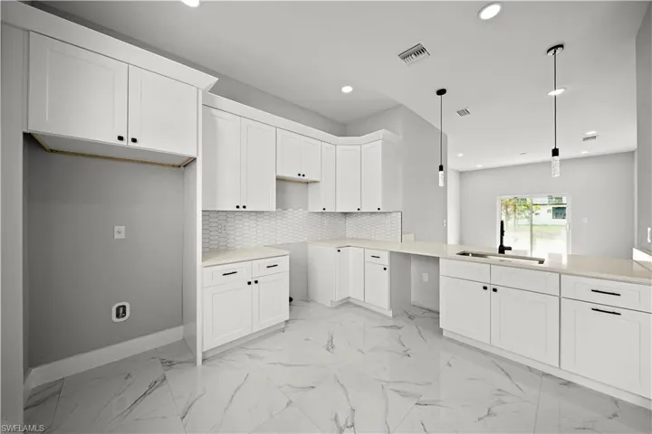 Kitchen featuring recessed lighting, light marble finish floors, white cabinetry, pendant lighting, and backsplash