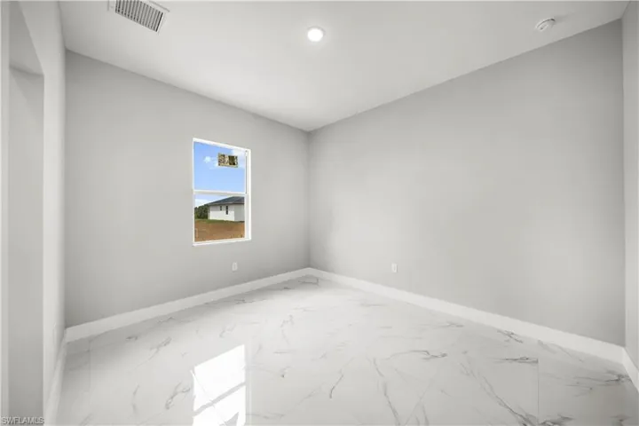 Empty room with marble look tiles, a smoke detector, and recessed lighting