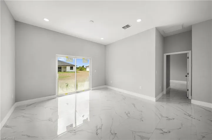 Empty room with light marble finish floors, attic access, and recessed lighting
