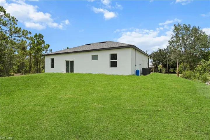 Back of house with a yard and stucco siding