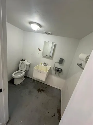Half bathroom featuring toilet and unfinished concrete flooring