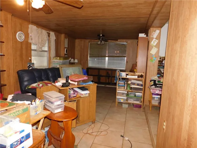 Kitchen with tile patterned floors, wood ceiling, wooden walls, and ceiling fan
