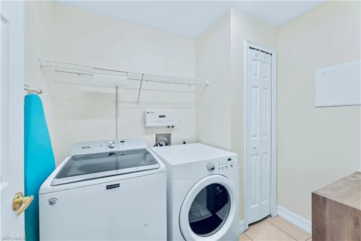 Laundry room with washing machine and dryer, hookup for a washing machine, and light tile floors