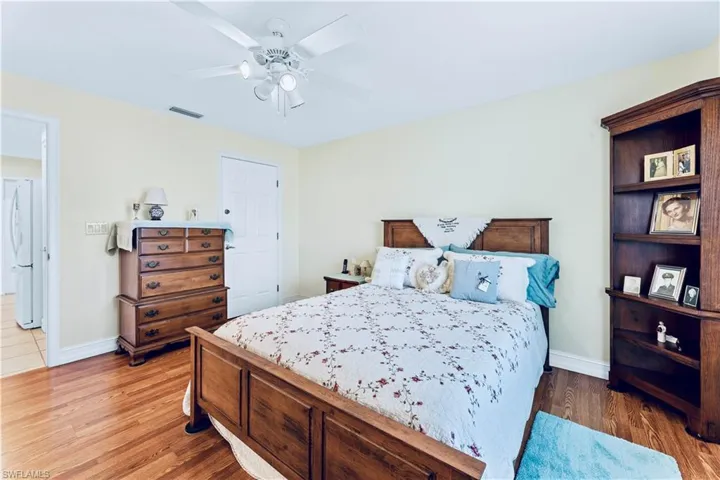 Bedroom with white refrigerator, hardwood / wood-style floors, and ceiling fan