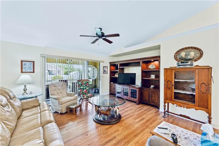 Living room featuring ornamental molding, ceiling fan, light wood-type flooring, and lofted ceiling