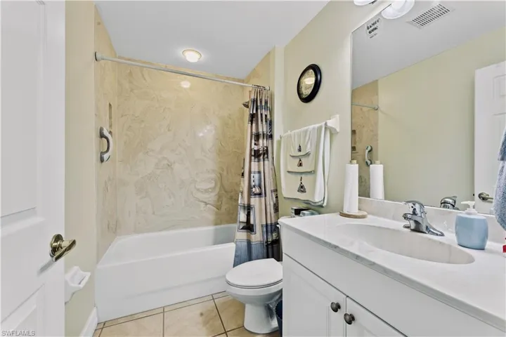 Full bathroom with shower / bathtub combination with curtain, tile flooring, oversized vanity, and toilet