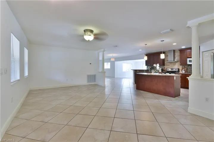 Spacious open-concept interior featuring light-colored tile flooring, white walls, and a ceiling fan