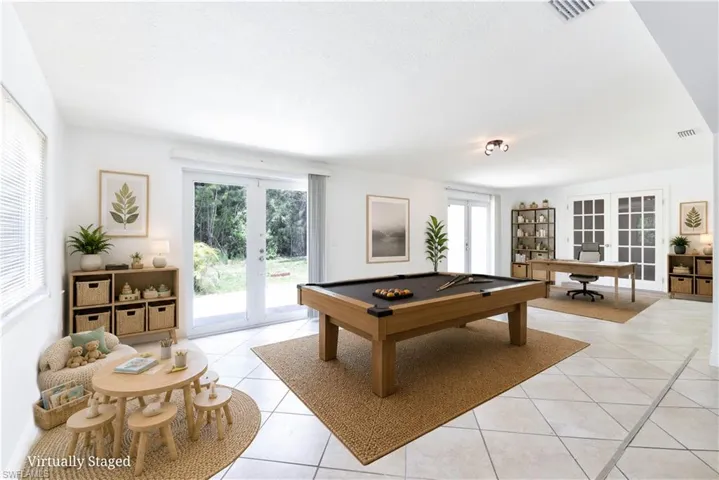 Spacious room featuring light-toned tile flooring, multiple sets of white French doors, and ample natural light from exterior windows
