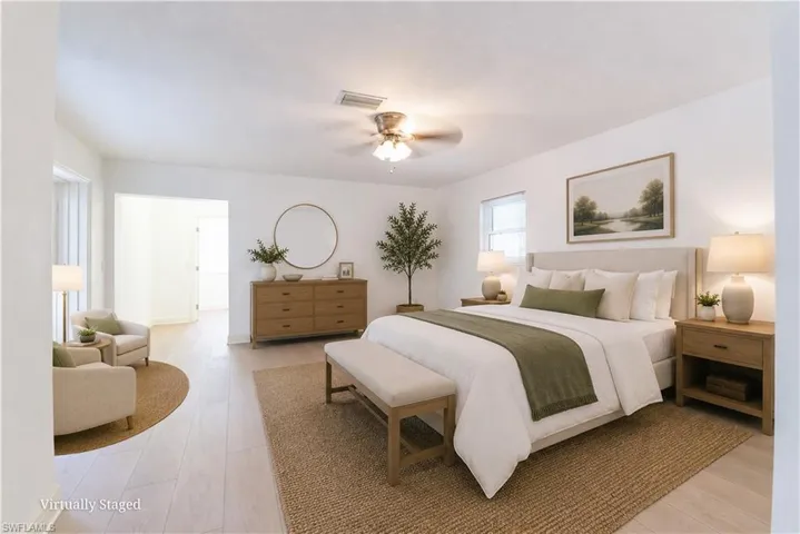 Spacious room featuring light wood-finish flooring, a ceiling fan, and ample natural light from multiple windows