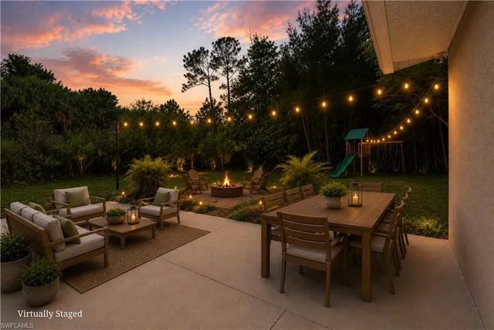 Expansive outdoor living area featuring a concrete patio, string lighting, and a built-in fire pit