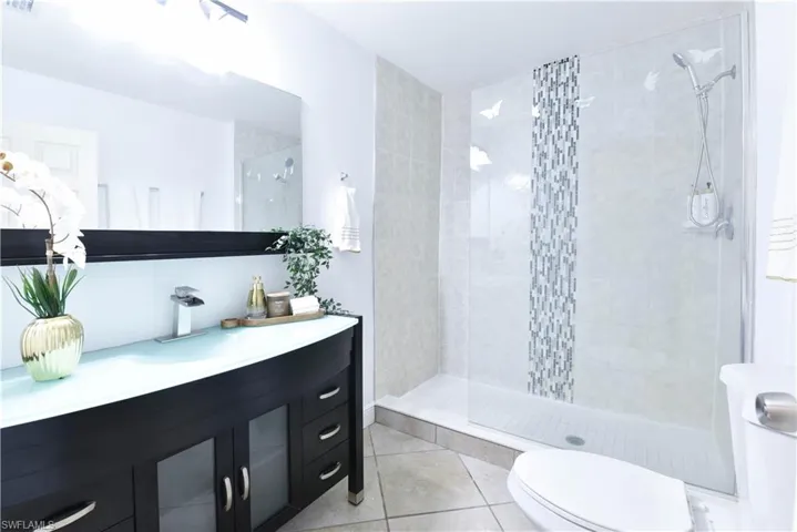 Vanity with a curved glass countertop and dark wood-finish cabinetry