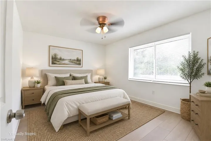Bedroom featuring light-toned flooring, white walls, and a ceiling fan with integrated lighting