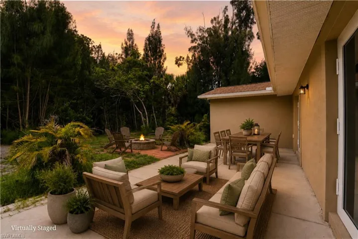 Expansive concrete patio with outdoor wall sconces and mature landscaping