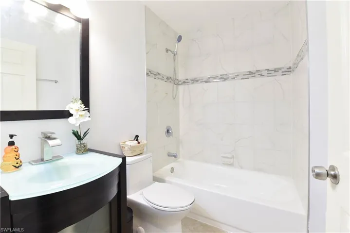 Bathroom featuring a vanity with a frosted glass basin, a contemporary faucet, and a large framed mirror