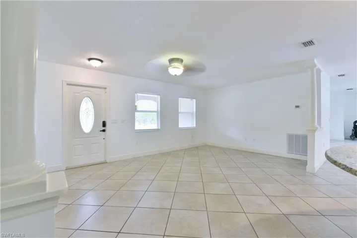 Entryway featuring neutral-toned tile flooring, a decorative front door with an oval glass insert, two windows for natural light, and recessed lighting