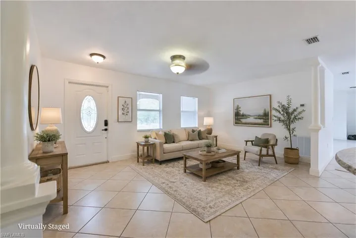 Spacious living area featuring diagonal tile flooring, a decorative front entry door with an oval glass insert, and recessed lighting