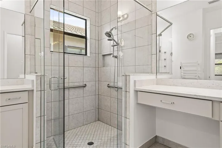 Walk-in shower with clear glass enclosure and tile surround